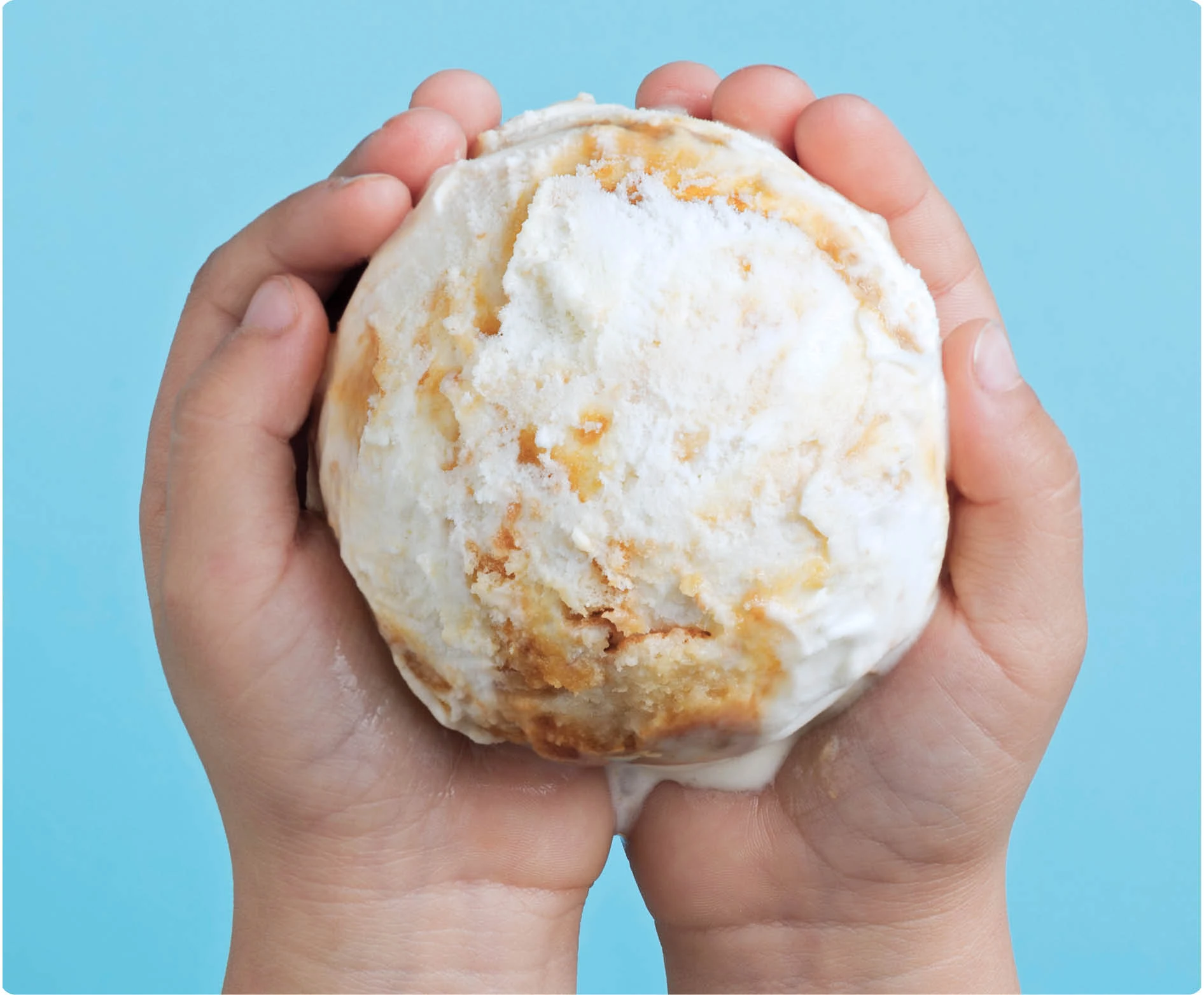 Manos sujetando una bola de helado